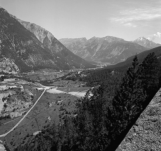 Vue lointaine du fort prise du fort du Randouillet, à 1000 m au sud. Au centre, vallon de Fontenil avec à droite le fort et, à gauche, le saillant de tête du fort des Têtes, dominé, en arrière plan, par le fort des Salettes. Au fond, vallée de la Durance et route du Montgenèvre.