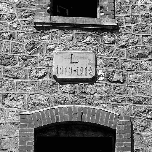 Baraquements de la Seyte : bâtiment L (m), façade sud. Plaque de datation de la construction.