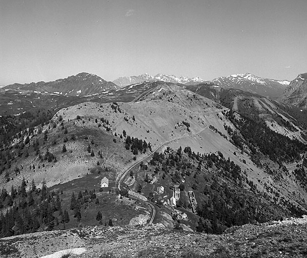 Cavalier supérieur, vue extérieure prise vers l'est. En bas, baraquements de la Cochette, au pied du sommet du même nom, masquant en partie le sommet de l'Ombilic. Derrière, crête du plateau du Gondran, avec, de gauche à droite, les ouvrages A et B, le col du Gondran, le sommet des Anges (couronné de l'ouvrage C) et ouvrage D. Plus en arrière, à gauche, sommet du Chenaillet. Au fond, sommets situés en Italie. Remarquer, au centre, la route militaire Seyte-Gondran.