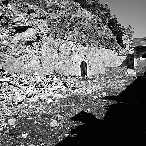 Magasin à poudre des pentes est. Vue intérieure de la cour. De gauche à droite, débris du local 4 (dépôt de projectiles chargés) et de lits militaires, entrée nord du magasin caverne, extrémité nord du mur d'enceinte et corps de garde défensif.