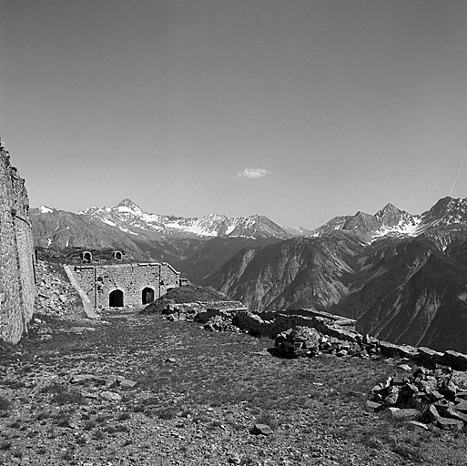 Casemate K et, au-dessus, batterie de 138, vus dans l'axe de la route de circulation intérieure du fort. A gauche, vue rasante de la casemate E et rampe d'accès à la batterie de 138.