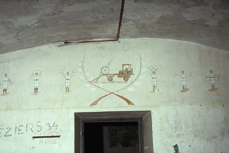 Bâtiment K. Rez-de-chaussée. Chambres de troupe. Fresque représentant un canon de 75 montant sur un camion plateforme, encadré par des soldats des transmissions faisant des signaux.