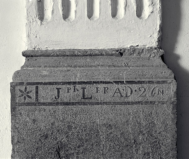 Inscription sculptée en réserve sur la base du pilastre gauche de la nef.