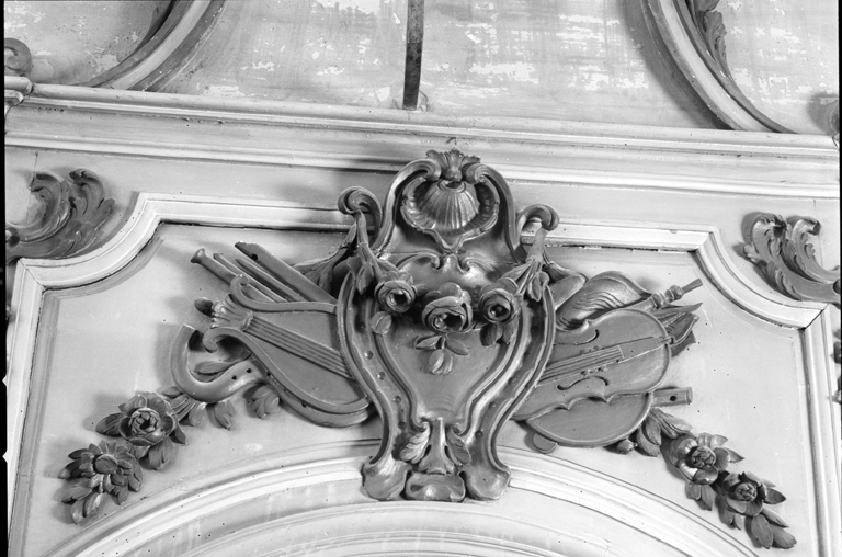Couronnement du siège de l'officiant : cartouche avec instruments de musique.