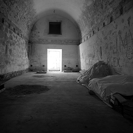 Fort Bas. Magasin à poudre F. Vue intérieure de la chambre à poudre prise vers l'entrée sud. A mi-hauteur des murs latéraux, les retraites destinées à supporter le plancher intermédiaire disparu.