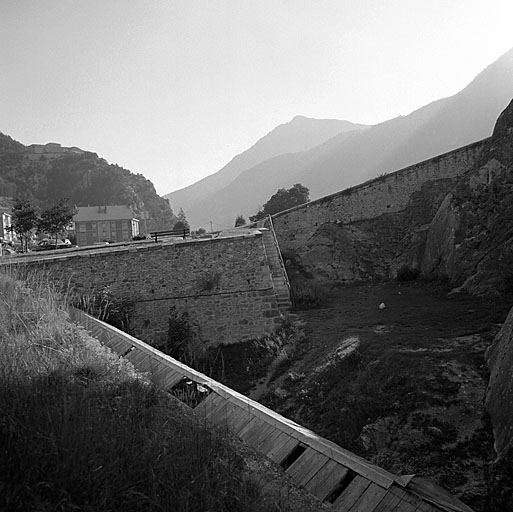 Extrémité nord-est de l'enceinte. Fossé du flanc droit de la demi-lune 30. Au premier plan, aqueduc couvert amenant l'au des Salettes et contrescarpe. A l'arrière-plan, de gauche à droite, fort des Salettes, trouée de la Durance et sommet du Janus.