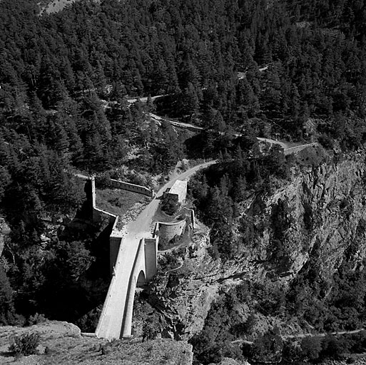 Vue plongeante prise depuis le château, dans l'axe du pont. Au fond, la route montant au fort des Têtes.