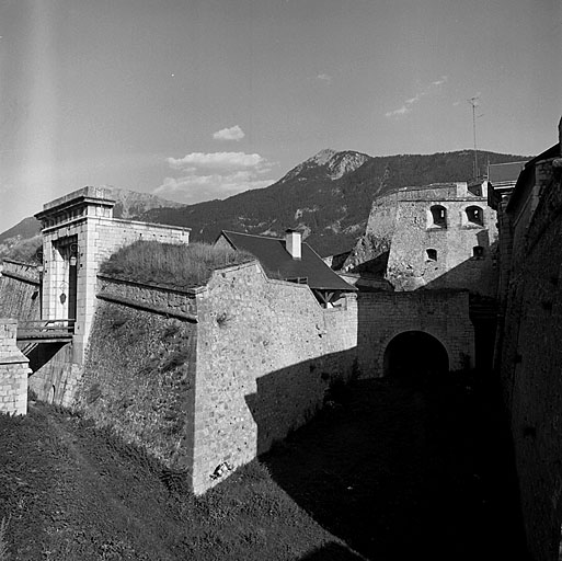 Front nord. Vue prise dans l'axe du fossé du corps de place, vers le sud-est. A gauche, demi-lune 30 et avant porte de Pignerol. Au fond, flanc 16. A droite bastion 17 et porte de Pignerol.