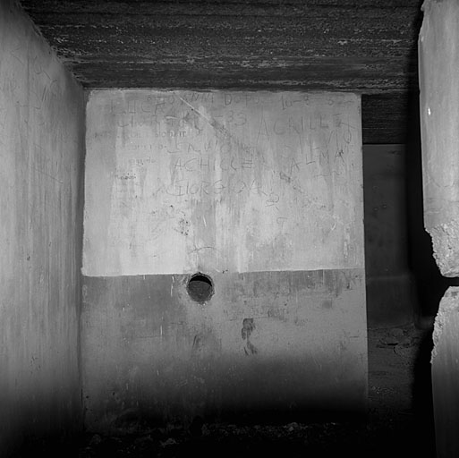 Bloc 2 (Entrée). Vue intérieure. Inscriptions murales, incluant un plan de l'ouvrage. L'orifice, dans le mur de masque, est celui d'une goulotte lance-grenades.