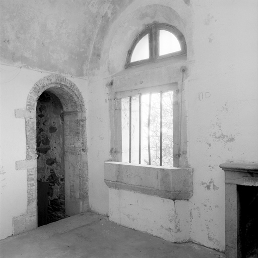 Tour réduit. Vue intérieure d'une pièce du rez-de-chaussée, à côté de l'entrée : de gauche à droite porte de l'escalier d'accès à la terrasse, fenêtre et cheminée.