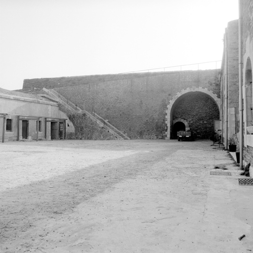 Extrémité est de la cour centrale. De gauche à droite : casemates d'officiers, escalier d'accès au parapet supérieur, passage est et façade des casernes.