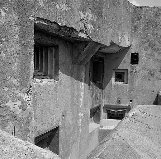 Bloc 2. Vue oblique de la façade. En haut, de gauche à droite : créneau JM, embrasure de 75-31 (flanquant Roche la Croix) et créneau FM de défense de façade. En bas, embrasures des deux mortiers de 81 mm, puis du mortier de 50 mm.