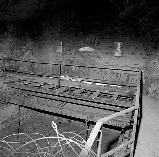 Fort supérieur. Front de tête. Casemate du pont roulant. Vue intérieure : tablier du pont, avec les barres de traction, à demi rentré dans le local. De part et d'autre, les trains de galets du chemin de roulement.