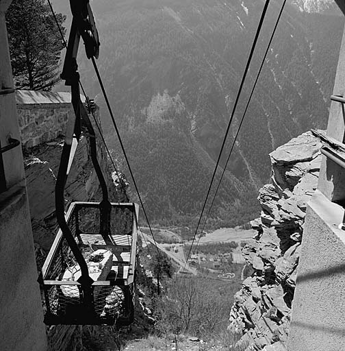 Téléphérique. Vue plongeante prise de la recette supérieure dans l'axe du câble. En bas, bâtiment de la recette inférieure. A gauche, benne et, derrière, mur d'enceinte du front sud.