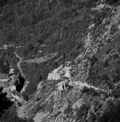 Batterie XII. Télévue du front de l'ouvrage prise de la route de Roche-la-Croix. A droite, casemate f de 95 mm. En bas, à gauche, caserne Pellegrin.