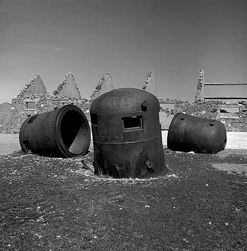 Cloches cuirassées en dépôt sur le terre-plein des écuries. Au centre, debout, cloche GFM A. A gauche, la même couchée. A droite, couchée, cloche lance-grenades.