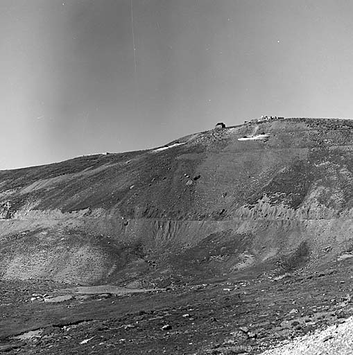 Le site de l'ouvrage vu de l'avant (est). A gauche, le bloc 4 (observatoire et cloche JM), à droite le bloc 3 (bloc d'infanterie de gauche et cloche JM). A la crête, vestiges des installations de chantiers abandonnées en 1939. En T, treuil de hissage. En dessous, route D64 Barcelonnette-Nice descendant vers les Fourches et Bouzieyas.