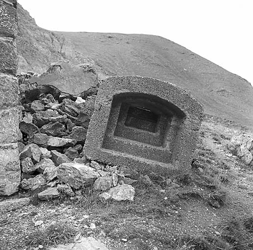 Elément de créneau préfabriqué en béton détaché dans un éboulement d'escarpe.