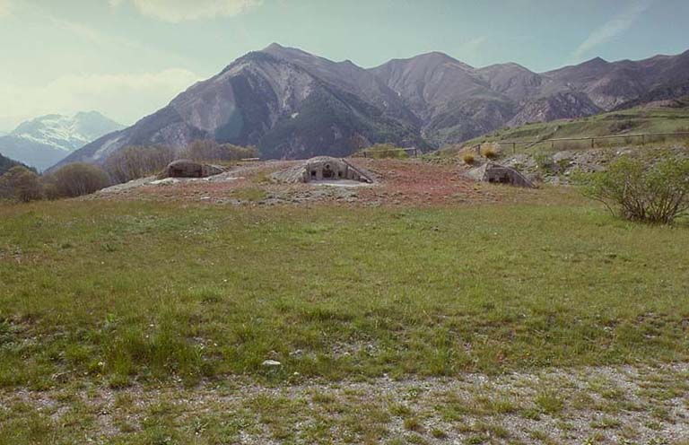 Ensemble de l'ouvrage vu de face. A gauche, cloche GFM 3 créneaux, à droite, les cloches JM frontales. Au fond, la pente portant l'observatoire de Serre la Plate.