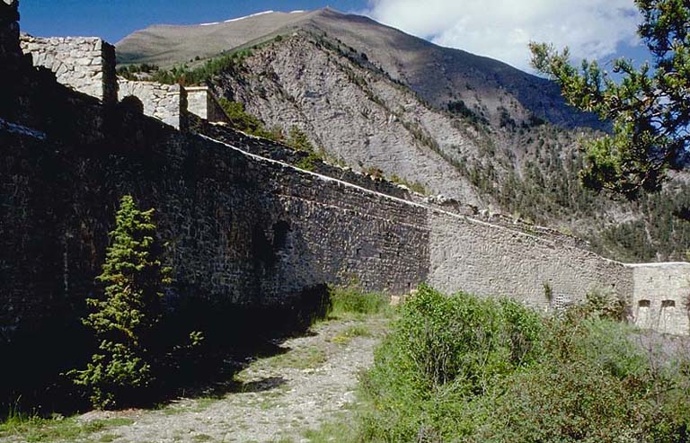 Front de tête. Vue oblique prise du saillant 5. A gauche, sortie de l'égoût du magasin à poudre. A droite caponnière double de tête. A l'arrière-plan, crête du Signal de la Condamine et les deux postes.