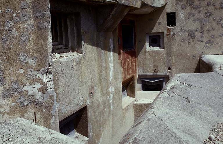 Bloc 2. Vue oblique de la façade. En haut, de gauche à droite : créneau JM, embrasure de 75-31 (flanquant Roche la Croix) et créneau FM de défense de façade. En bas, embrasures des deux mortiers de 81 mm, puis du mortier de 50 mm.