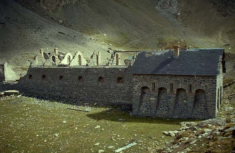 Vue, en premier plan, du casernement et du fond de la combe. En haut, à l'extrémité droite, batterie de Viraysse. Au centre, au pied du rocher isolé se trouve la source dont le captage alimente en eau le casernement.