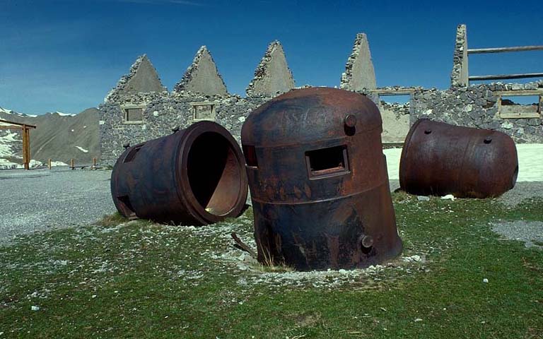 Cloches cuirassées en dépôt sur le terre-plein des écuries. Au centre, debout, cloche GFM A. A gauche, la même couchée. A droite, couchée, cloche lance-grenades.