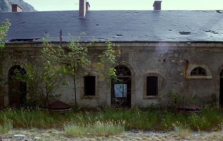 Fort moyen. Caserne A. Au premier niveau, façade nord prise du terre-plein. Devant le bâtiment, margelle d'un oculus d'éclairage du passage couvert.