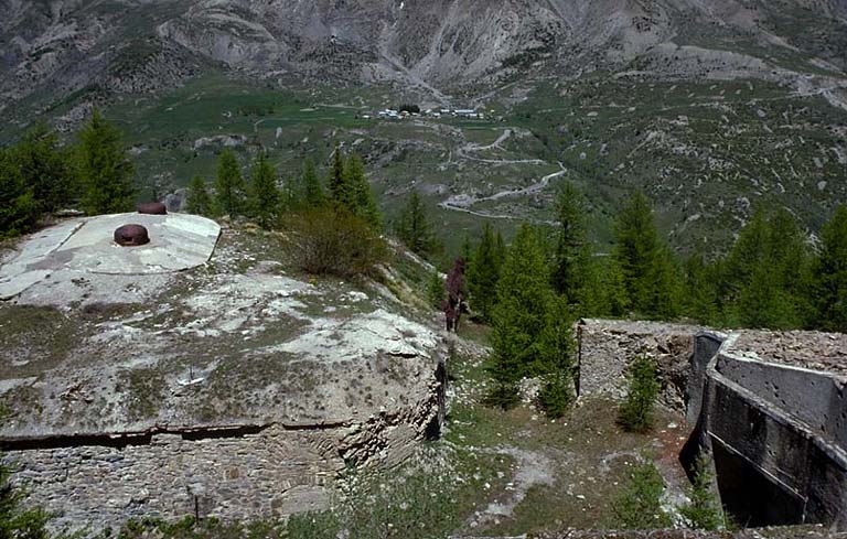 Vue prise du haut du bloc 3, dans l'axe du fossé du front de tête. A gauche, le bloc 4 (observatoire cuirassé). Au fond, le village de Saint-Ours avec, à l'extrême droite, l'ouvrage haut de Saint-Ours. A droite, haut du bloc 2.