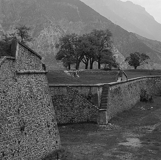 Vue rapprochée de la place d'armes rentrante à droite de la demi-lune 43 prise du pont de la porte de Briançon. (Remarquer le pas-de-souris d'accès depuis le fossé). A gauche mur de gorge de la demi-lune.