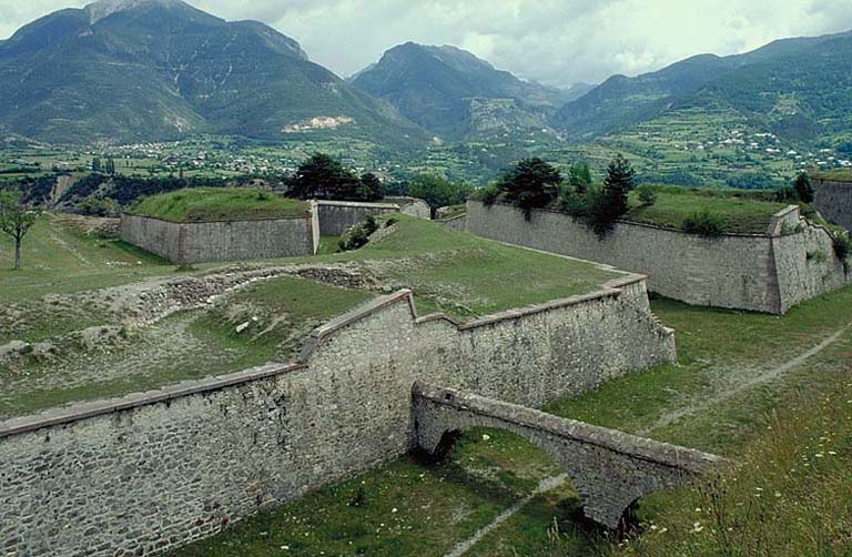 Front d'Eygliers. Vue prise du haut de la face droite du bastion 2. A gauche, contregarde 63 et, derrière, la demi-lune 42. Au premier plan, chemin couvert et, dans le fossé, l'aqueduc de la conduite de la source de Loubatière.