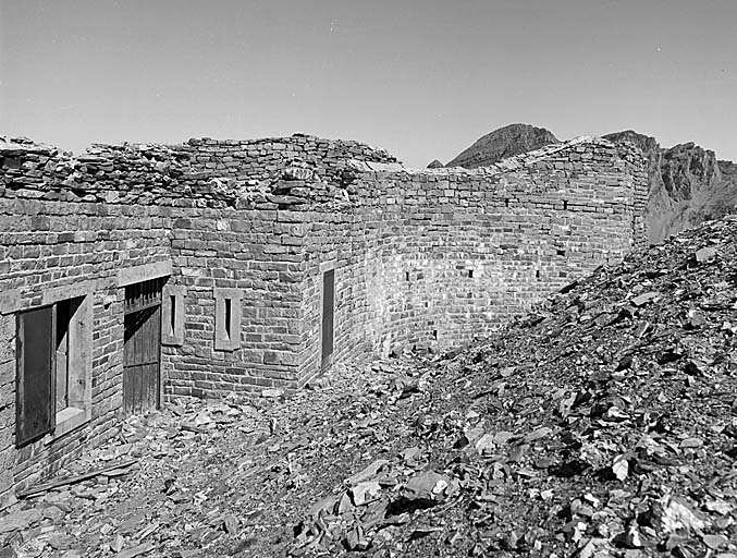 Flanc sud-est du casernement. Au premier plan, à droite, masse couvrante latérale. De gauche à droite, fenêtre de la cuisine, porte du couloir de fond et créneaux à fusil de la caponnière.