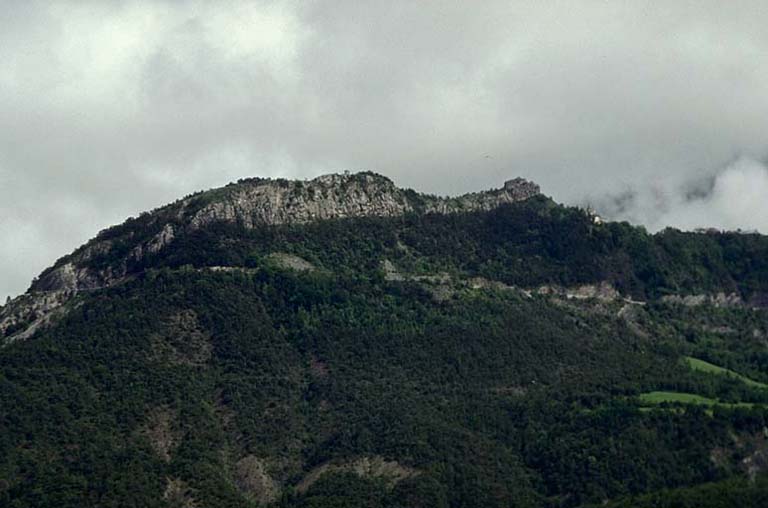 Vue de situation. Ensemble du site vu de l'ouest. Le fort au niveau du point culminant à droite ; la tour à mâchicoulis au niveau du point culminant plus à gauche.