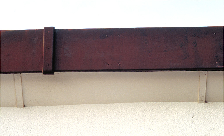 Façade sud, second niveau. Bandeau métallique d'entablement avec agrafe de fixation. Détail.