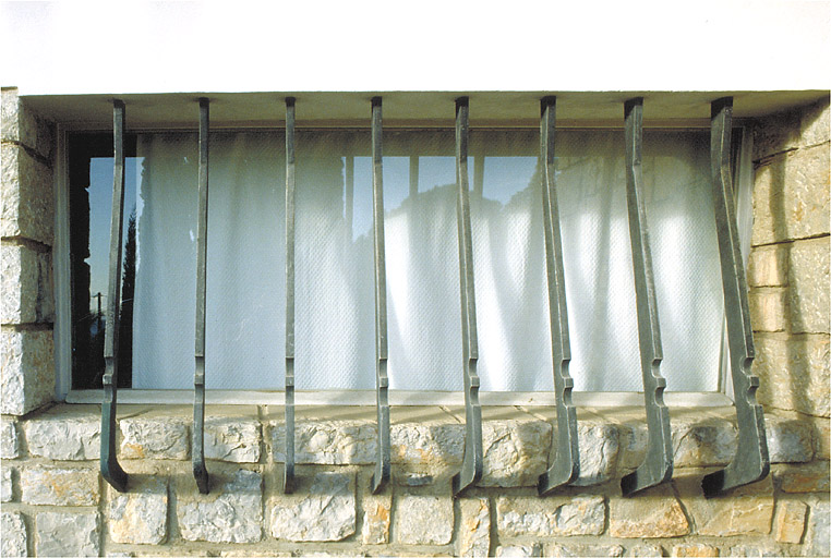 Vue de détail d'une grille en fer-forgé située à l'étage, sur la façade sud.