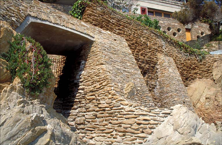 Vue en contreplongée du mur de soutènement au sud avec portail au premier plan, depuis le bord de mer.