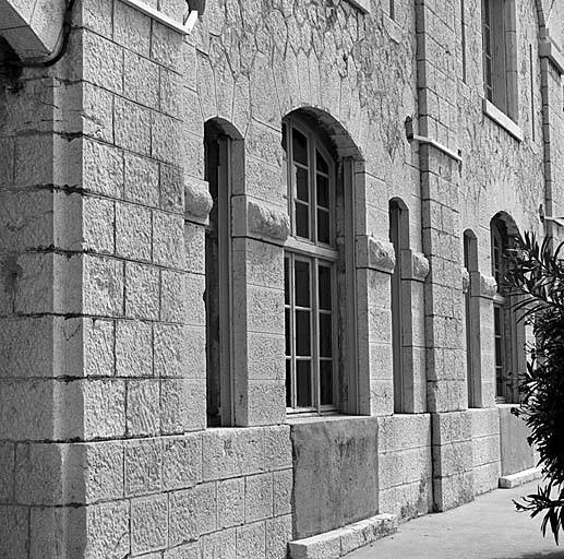 Bâtiment b (caserne). Vue oblique de la façade. Dans les joues des baies, les fers U destinés à recevoir les rails de blindage du temps de guerre.