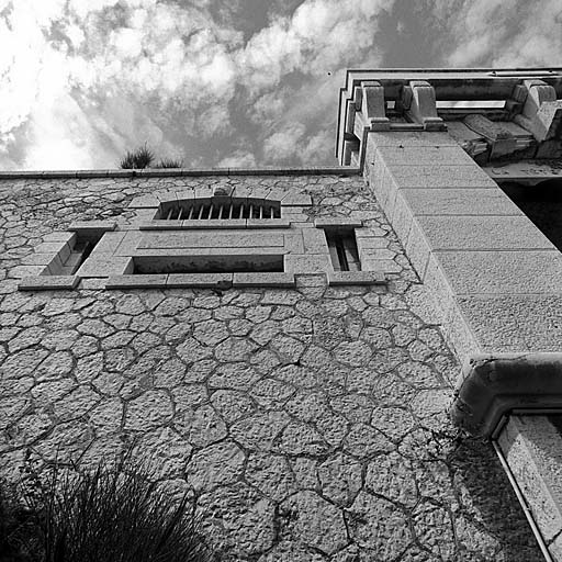 Bâtiment a. Entrée du fort. Vue oblique rapprochée des créneaux de fusillade et du pilastre de gauche de l'entrée et des machicoulis.