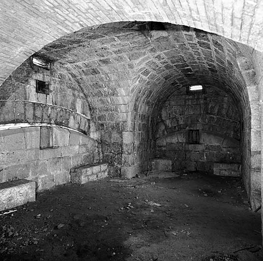 Aile gauche du bâtiment a. Premier sous-sol, local 7 (chambre de tir triple). Vue intérieure. A gauche, créneau de pied et embrasure à canon tirant sur le col d'Eze. . A droite, créneau de pied et embrasure à canon flanquant l'escarpe sud-ouest du fort.