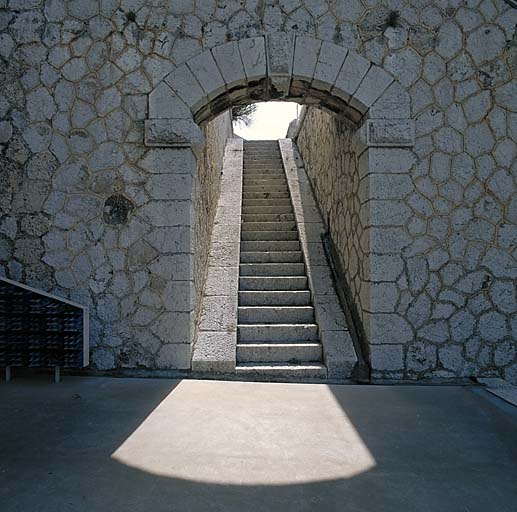 Bâtiment a. Escalier-rampe montant vers les dessus.