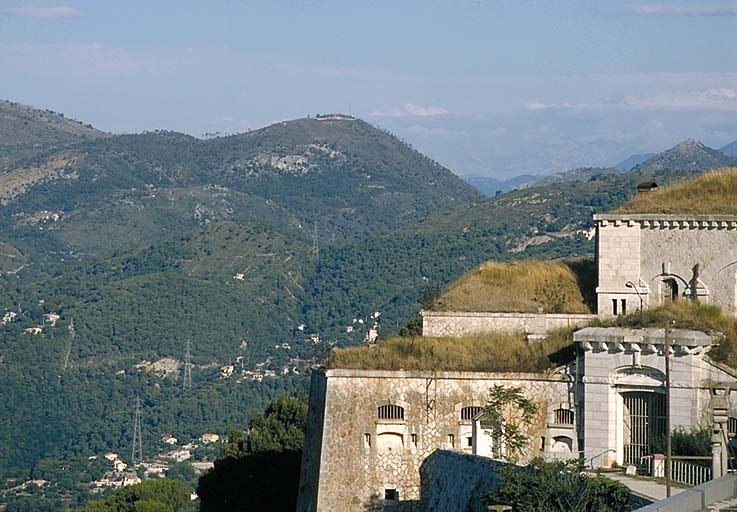 Vue lointaine des Monts chauves prise des abords du fort. Au premier plan, à droite, extrémité du bâtiment a. Au deuxième plan, à gauche, fort du Mont Chauve d'Aspremont. A droite, ouvrage du Mont Chauve de Tourette. ; La Trinité. Fort de la Drète.