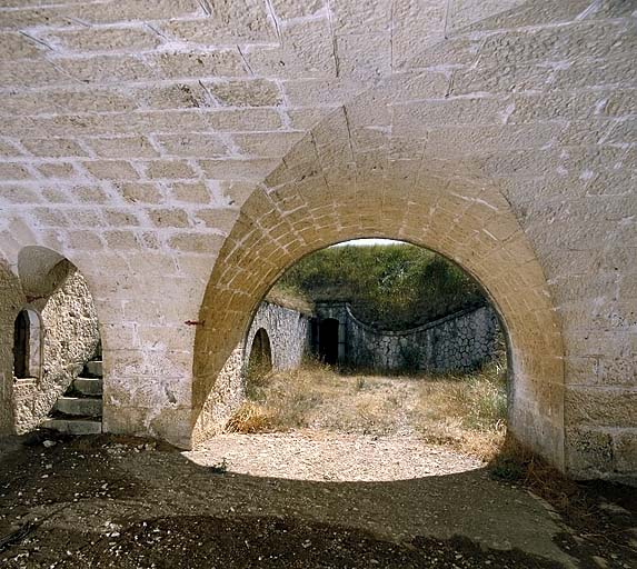 Rue du Rempart. Front nord. Passage couvert de la traverse VI. Au fond, porte de la gaine d'accès à la caponnière VIII. Au premier plan, à gauche, escalier montant à la plateforme 2.