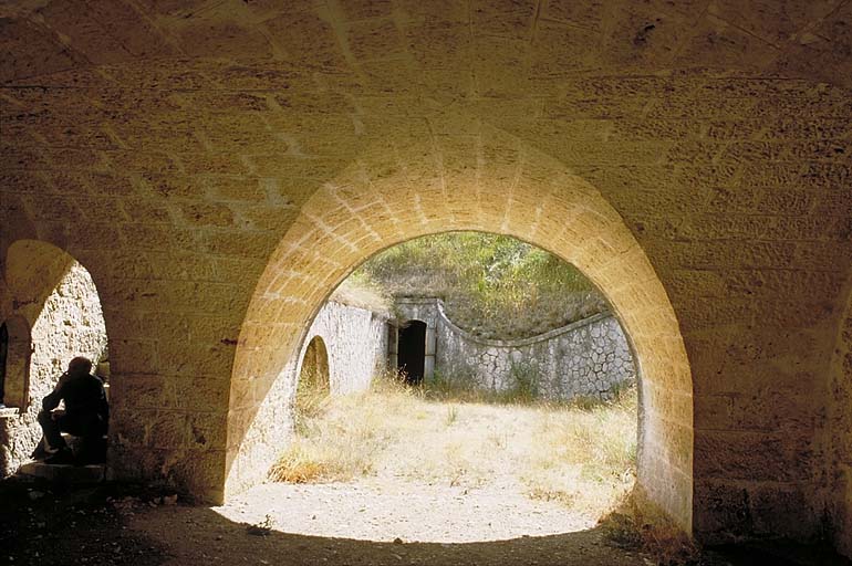 Rue du Rempart. Front nord. Passage couvert de la traverse VI. Au fond, porte de la gaine d'accès à la caponnière VIII. Au premier plan, à gauche, escalier montant à la plateforme 2