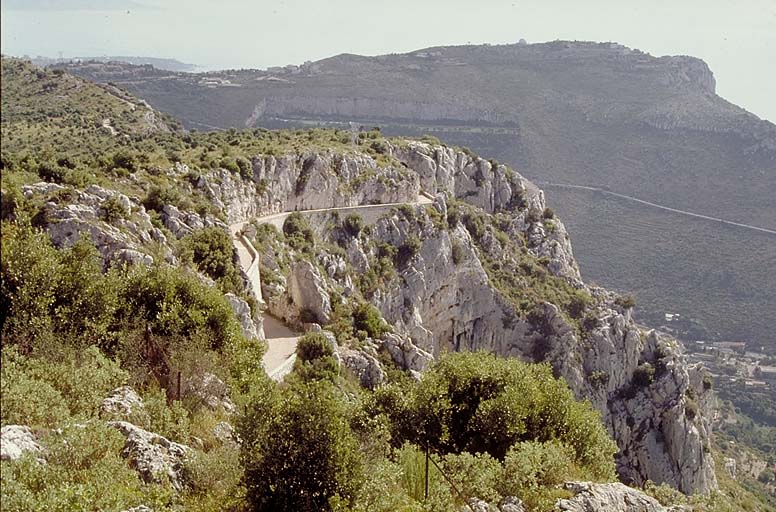 Organes des intervalles ou extérieurs aux forts. Crête de La Forna. Vue de la route militaire prise vers l'est. A l'arrière-plan, crête et et fort de la Tête de Chien. Au centre, éperon rocheux abritant le tunnel de Simboula.