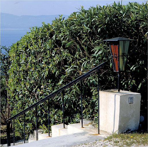 Détail de la rampe en fer-forgé et d'une lanterne située sur l'escalier dans le jardin.