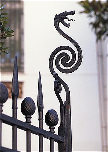 Détail : figure en fer forgé située à l'extrémité supérieure de la grille du portail d'entrée.