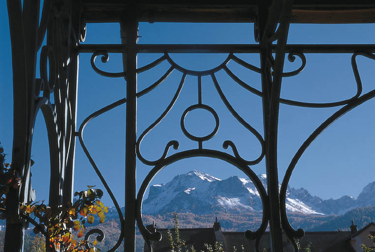 Véranda. Détail de la ferronnerie. Au loin, la silhouette du Chapeau de Gendarme.