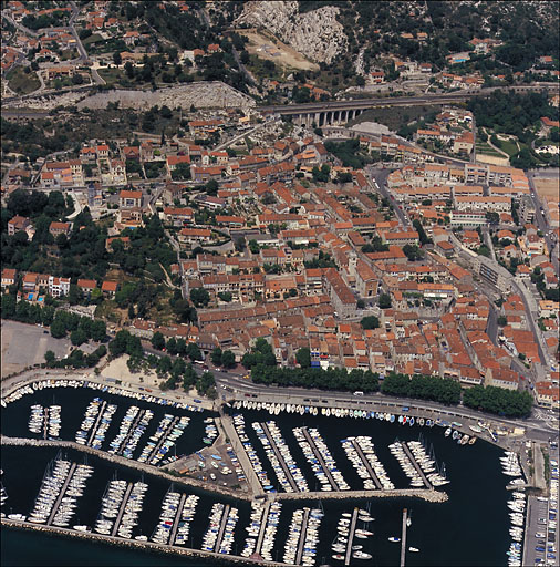 Vue aérienne du quartier de l'église prise du sud en direction du nord ; au premier plan le port et la section du chemin du Littoral dite Plage de l'Estaque (RN 568b), à l'arrière-plan la voie ferrée et le viaduc du Marinier. Le quartier est délimité à gauche par la traverse Mistral longeant le jardin de la villa Mistral et à droite par le boulevard Roger-Chieusse.