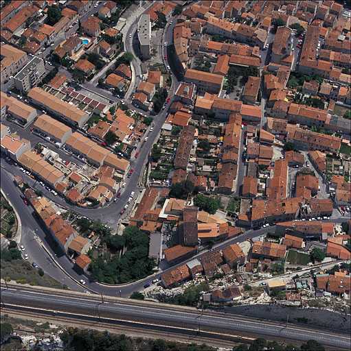 Vue aérienne, prise du nord en direction du sud. Au premier plan la jonction du boulevard Roger-Chieusse et du chemin de la Nerthe, le viaduc et le parc du pensionnat Saint-Joseph. A l'arrière-plan à droite, l'église. Au centre, les lotissements du début du siècle : l'immeuble à logements Chieusse et ses jardins en bandes, les maisons de ville à jardins derrière de la traverse Léon-Véray.