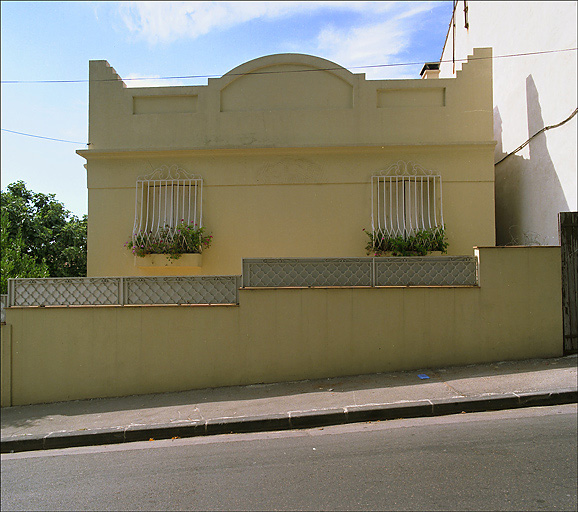 Vue de la façade est prise depuis la voie, fronton art déco.